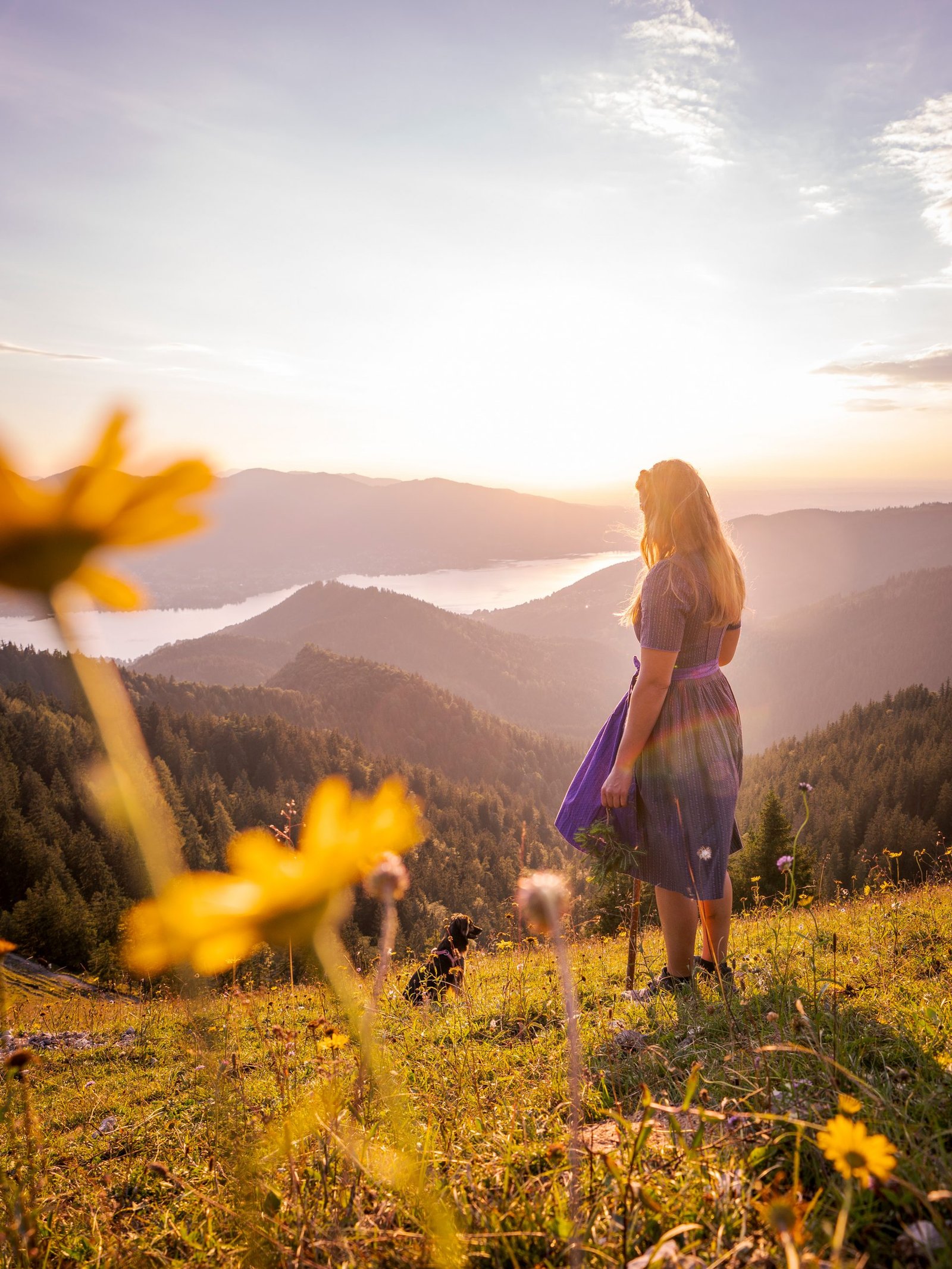 Frau im Dirndl blickt bei Sonnenuntergang über den Tegernsee – Ausblick nahe dem Gästehaus Sonnenbichl