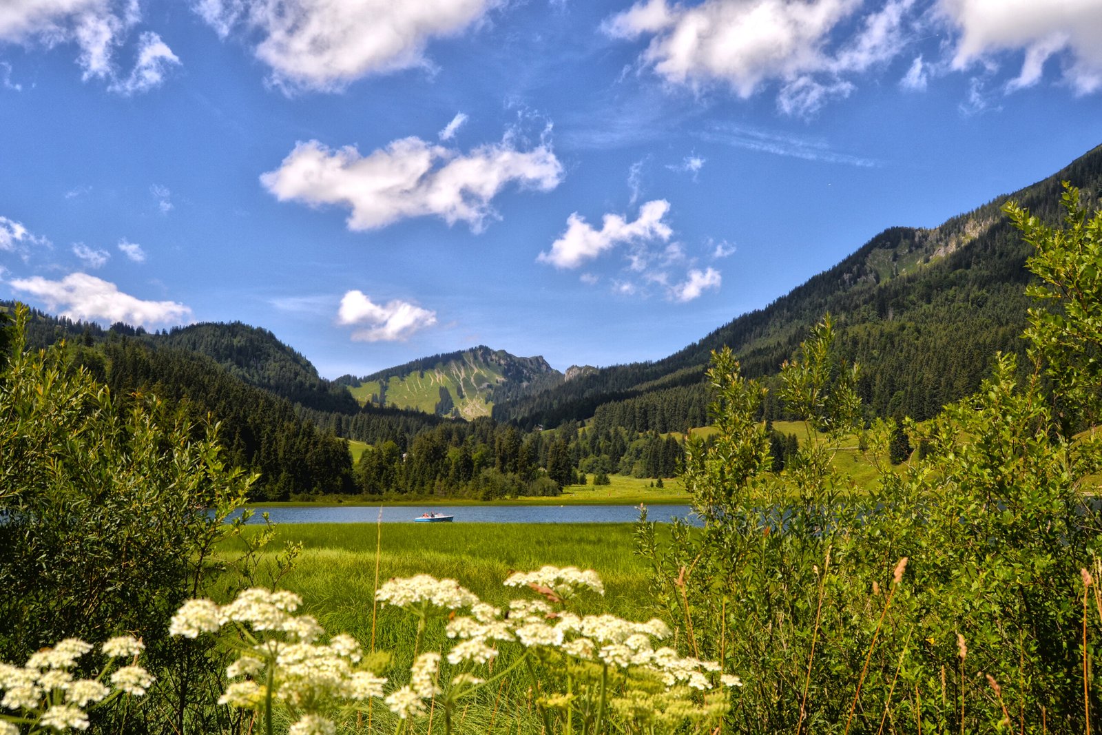 Blick auf einen ruhigen Bergsee mit Boot inmitten der Alpenlandschaft bei Fischbachau – Naturerlebnis nahe Gästehaus Sonnenbichl